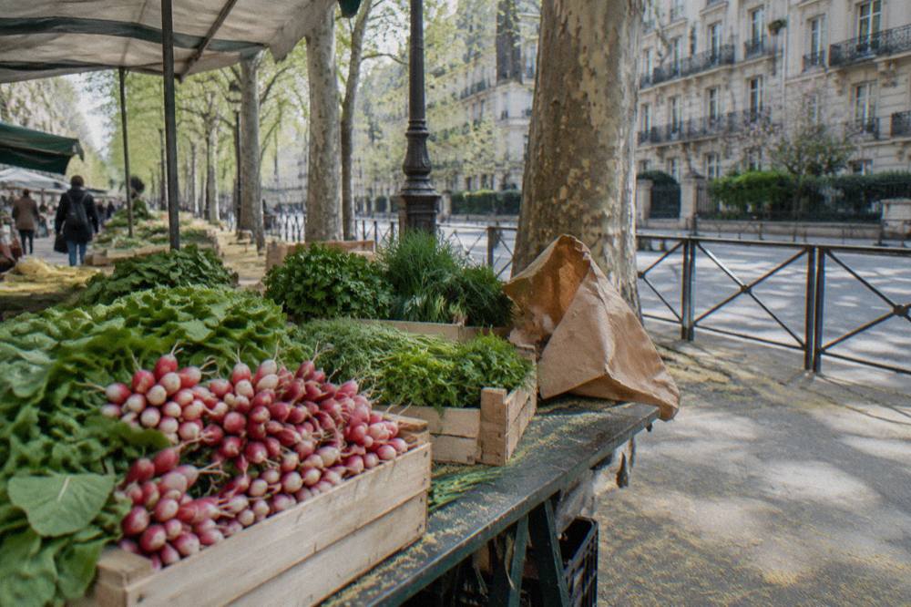 Outdoor market stalls with crates of fresh produce on a Paris street in the morning